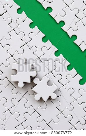 The Green Path Is Laid On The Platform Of A White Folded Jigsaw Puzzle. The Missing Elements Of The 