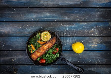 Grilled Salmon Fillet In A Frying Pan, Vegetables, Arugula With A Lemon. On The Cutting Board And Wo