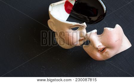 Broken Doll Faces And Blood Isolated On Grunge Black Background With Blood Spatter. Conceptual Image