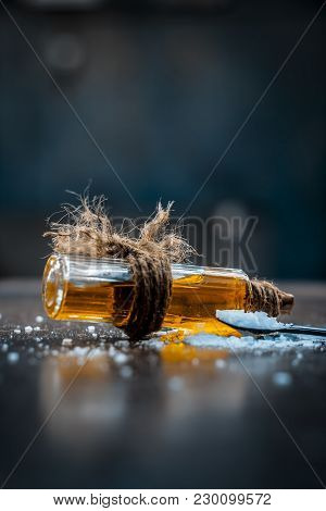 Close Up Of Aurvedic Herb Camphor Powder In A Small Spoon And Its Oil On Brown Wooden Surface In Dar