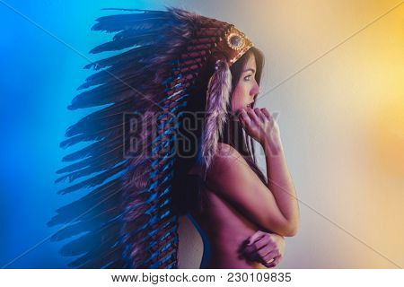 Beautiful young brunette with big American Indian plume of brown feathers. has long black hair