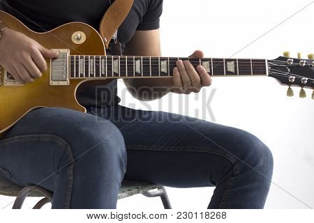 A Man Is Sitting On A Chair And Playing An Electric Guitar On A White Background