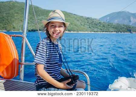 Cute Boy On Board Of Sailing Yacht On Summer Cruise. Travel Adventure, Yachting With Child On Family