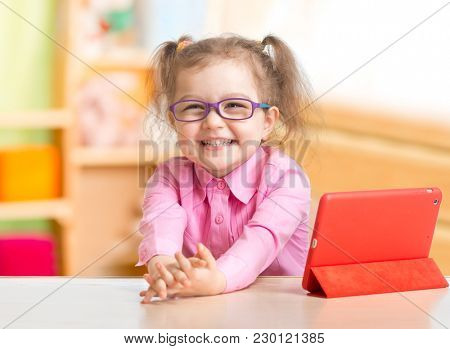 Smart kid in spectacles reading books in her room