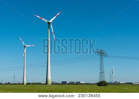 Wind Turbines And Overhead Lines On A Sunny Day Seen In Germany
