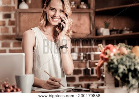Phone Call. Delighted Positive Cheerful Woman Holing Her Phone And Making A Phone Call While Being R