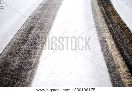 Car Tracks In Snow On Winter Asphalt Road.