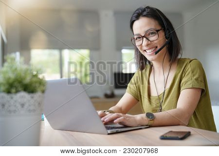 Teleoperator working in office with laptop and headset on