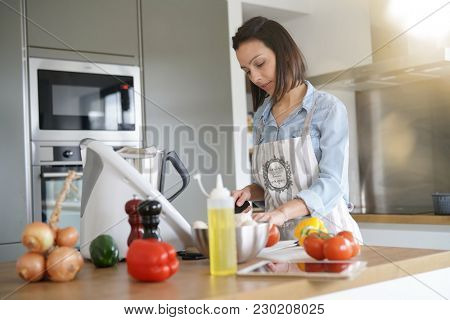 Woman using kitchen robot to prepare dinner