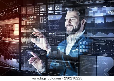 Easy Work. Cheerful Smart Elegant Programmer Smiling And Feeling Lucky While Being In His Futuristic