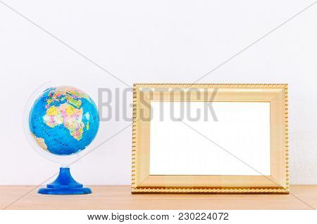 Photo Frame And Global Ball Toy On Wooden Table