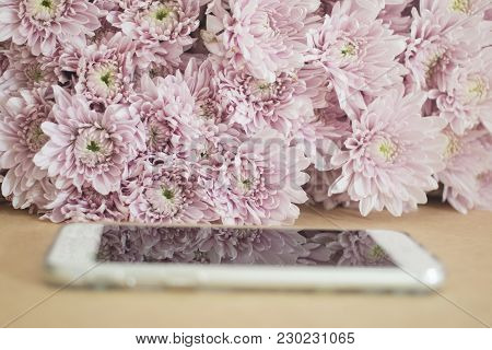 Smart Phone With Pink Flowers Background. Selective Focus