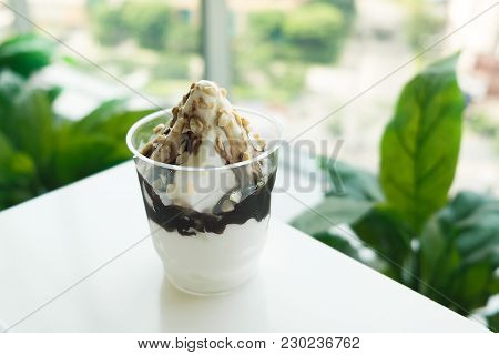 Ice Cream Sundae With Chocolate And Walnut On Plastic Glass On White Table