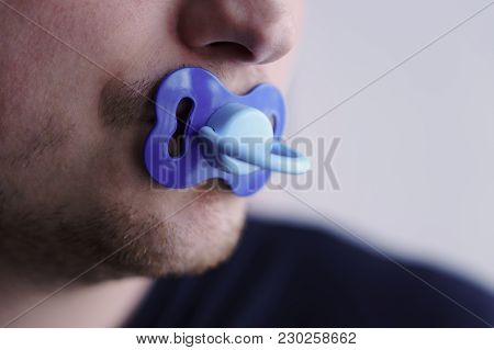 A Young Man Holds A Blue Pacifier In His Mouth