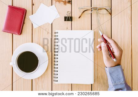 Hands Writing On A Wooden Table With Office Supplies