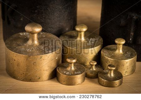 Old Iron 1kg Weight And Smaller Brass Weights For A Kitchen Scale Standing On A Table