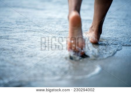 Woman Barefoot Walking On The Beach With Travel Concept.