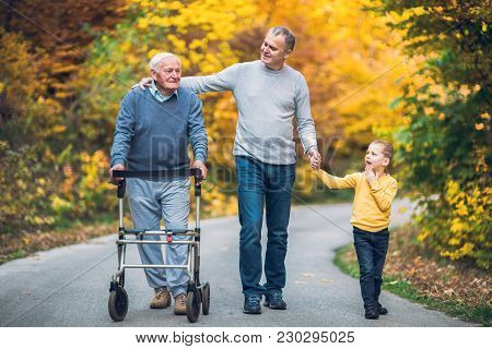 Elderly Father Adult Son And Grandson Out For A Walk In The Park.
