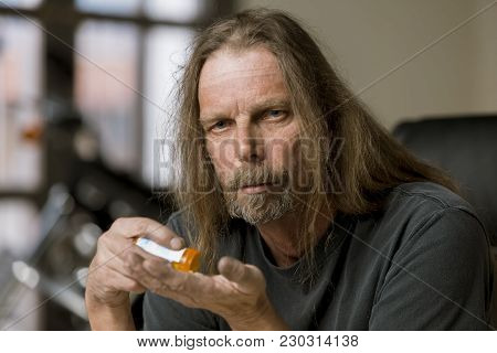 Man Holding An Opioid Pill And Bottle