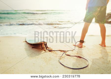 Close Up Feet Of Male Surfer, Who Stands On Sea Or Ocean Beach And Studies The Waves Before To Enter
