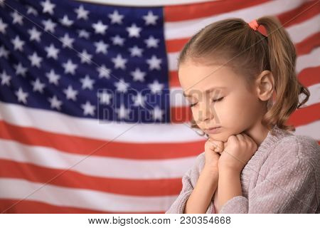 Cute little girl praying for America and flag on background