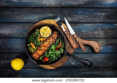 Grilled Salmon Fillet In A Frying Pan, Vegetables, Arugula With A Lemon. On The Cutting Board And Wo