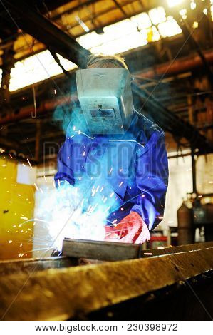 Welder For His Work. Welding Sparks On Production Background
