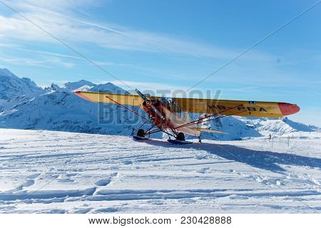 Mannlichen, Switzerland - December 31, 2013: Yellow Airplane In Mountain Peaks In Mannlichen In Wint