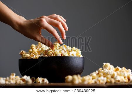 The Hand Reaches For A Bowl With Tasty Popcorn.