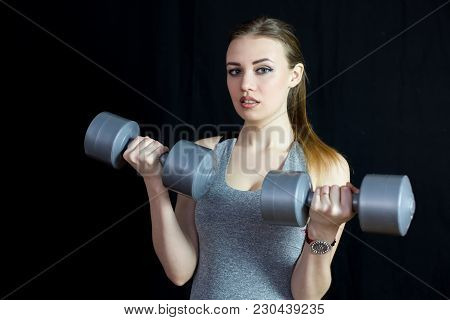 The Athlete Is Engaged With Heavy Dumbbells On A Black Background.