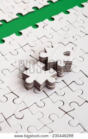 The Green Path Is Laid On The Platform Of A White Folded Jigsaw Puzzle. The Missing Elements Of The 