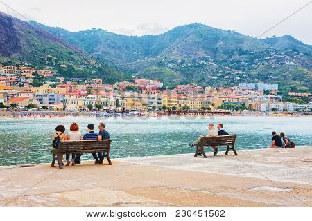 Cefalu, Italy - September 26, 2017: Seaside With People Sitting On The Benches In Cefalu Old Town, P
