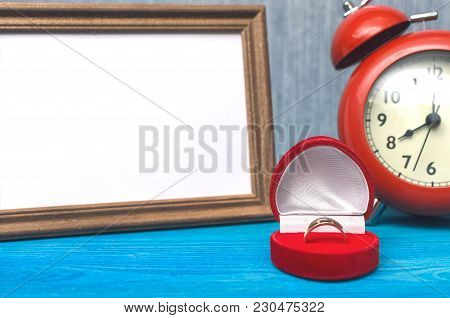 Wedding Ring In A Gift Present Box And Empty Photo Frame Of A Loved One Copy Space And Red Alarm Clo