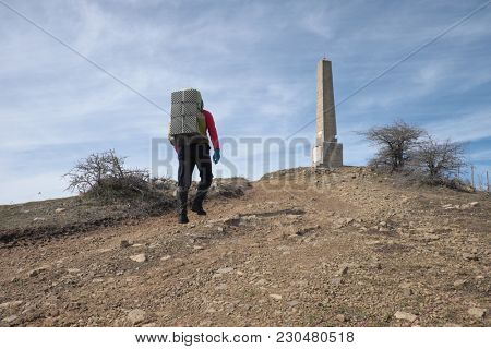 man with backpack walking on the slope to Nelson Obelisk in Nebrodi Park, Sicily