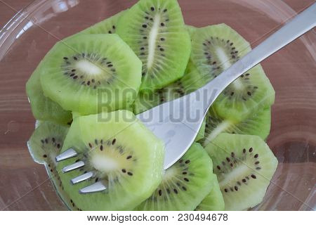 Bowl Full With High In Vitamins Kiwi Fruit Slices And Fork Isolated On Wooden Background