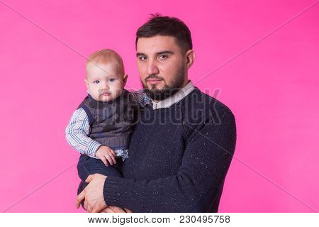 Happy Father Holding Baby Son In Hands Over Pink Background.