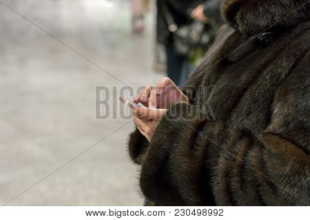 Woman In A Fur Coat Using A Smartphone