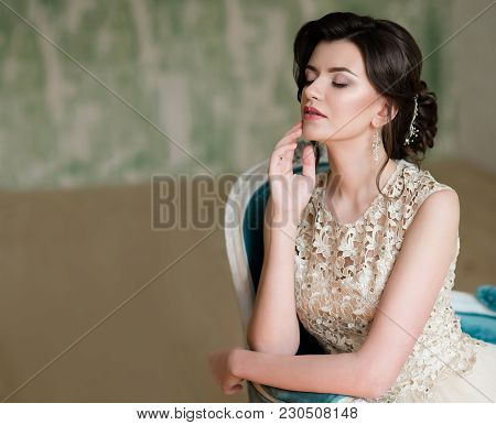 Half Length Portrait Of Brunette Smiling Woman Dressed In Sleeveless Light Evening Dress.