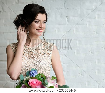 Half Length Portrait Of Brunette Smiling Woman Dressed In Sleeveless Light Evening Dress.