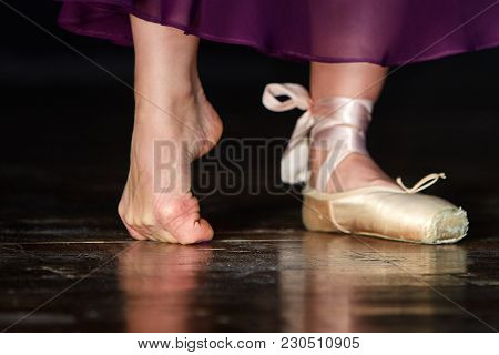 Elegant Ballerina In Light Satin Purple Training Skirt Is Posing In The Studio On The Dark Backgroun