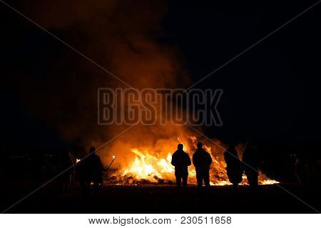 Silhouettes Of People In Frontof Big Fire