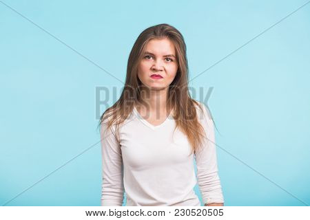 Portrait Of Young Angry Woman On Blue Background.