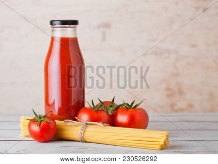 Glass Bottle Of Tomato Paste With Raw Spaghetti And Fresh Organic Tomatoes On Wooden Background