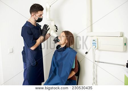 Assistant Dentist Makes An X-ray Of Teeth To A Young Woman In A Modern Medical Center