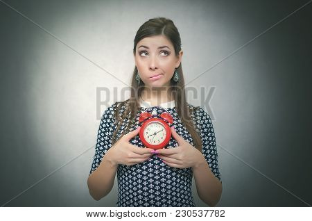 Guilty Look Woman Holding In Hands Alarm Clock And Hides Her Eyes By Looking Aside. Latecomer Studen