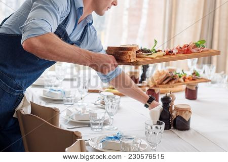 Waiter Serving Meat Dishes On Wooden Board At Restaurant, Close Up View