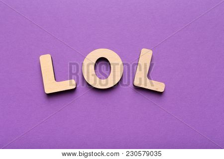 Word Lol Spelled Out With Wooden Letters On Violet Background. Abbreviation Stands For Laugh Out Lou