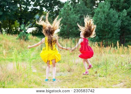 Two Beautiful Little Girls  Jumping And Dancing At Sunny Summer Day. Happy Kids Concept