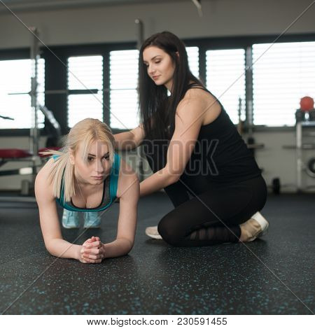Woman Doaing A Plank Workout In Gym With Her Personal Coach