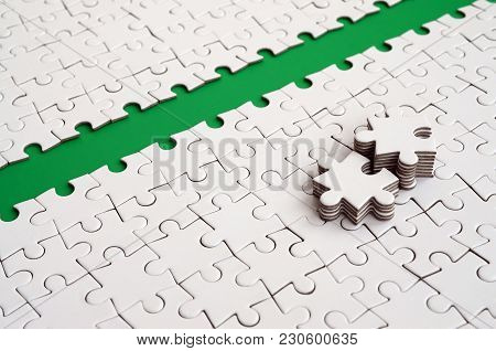 The Green Path Is Laid On The Platform Of A White Folded Jigsaw Puzzle. The Missing Elements Of The 
